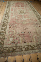 Distressed vintage Oushak runner with faded blush field, geometric palmette, and olive borders.