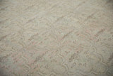 Faded floral palmettes and scalloped panels on a distressed vintage Oushak carpet pile.
