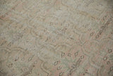 Distressed pile texture showing faded dusty pink and pale green floral motifs.