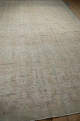 Close-up of distressed Oushak rug, worn pile, faint floral pattern, machine-finished edge.