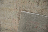 Distressed Oushak pile showing wear, pale pink and green hues, alongside its machine-finished edge.