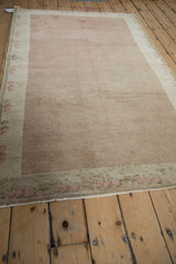 Distressed Oushak rug with pale coffee brown field and blush blossoms on ivory border.