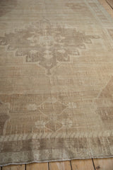 Distressed Oushak rug texture with low pile, subtle raised warps, and muted beige tones.