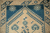 Distressed pile and geometric hook and latch motifs in blue and sand on a vintage Dosemealti rug.