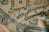 Distressed vintage Dosemealti rug with beige hand-knotted pile and blue hook and latch motifs.