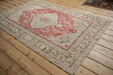 High-angle view of a vintage distressed Kayseri rug with its faded red and ivory floral medallion pattern.