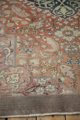 Distressed vintage Sivas rug corner, terracotta field, pink border, delicate blossom motifs, machine-finished edge.