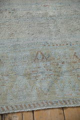 Soft pile of a distressed Turkish runner, showing faded geometric patterns in blue and dusty copper.
