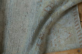 Folded distressed Turkish runner pile displays worn texture, powder blue, bronze, and finished edge.