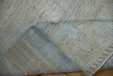 Muted platinum and blue distressed pile, with the hand-knotted foundation revealed.