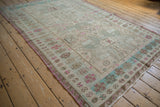 Distressed Soumac rug border with geometric gul, pinwheel florals, and color abrashes in pink and seafoam.