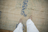 Distressed Oushak carpet featuring worn cream pile, cobalt blue, and sea foam green motifs.