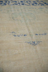 Distressed cream Oushak texture, showing heavy abrashes and faint blue design elements.