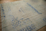 Distressed Oushak carpet featuring worn pile, heavy abrashes, and faded cream and cobalt blue.