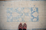 Distressed Turkish Oushak rug featuring soft blue floral patterns and heavy abrashes on ivory.