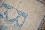 Distressed Oushak rug, featuring heavy abrashes on soft ivory pile with aqua blue florals.