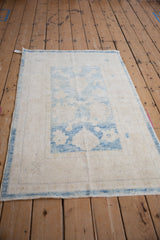 Distressed Oushak rug displaying faded powder blue floral motifs and abrashes.