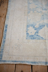 Distressed ivory and powder blue Oushak rug with soft wool pile and intact side cord selvage.