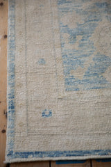 Distressed Oushak rug edge, blue side cord selvage, and abraded aquatic blue floral field.