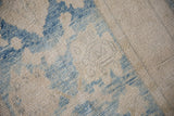 Distressed Oushak rug close-up: heavy abrashes on soft blue and ivory floral pile.