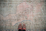 Heavily abrashed texture of a vintage Sparta rug with dusty rose and faded green florals.