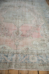 Distressed Sparta carpet detail with abrashed dusty rose field, faded blue floral motifs, and vine border.
