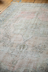 Heavily abrashed field with faded dusty rose, blue, and ivory floral patterns.