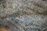 Folded vintage Sparta carpet with distressed texture, faded dusty rose and denim blue patterns.