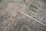 Distressed dusty rose pile with faded blue patterns, showing hand-knotted foundation at rug corner.