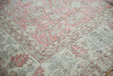 Distressed Sparta carpet corner: soft blush, ivory, green floral motifs with evident wear.
