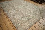 Distressed Tabriz carpet with faded floral motifs in soft beige, green, and dusty rose.