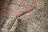 Distressed vintage Sparta carpet's worn pink pile, revealing knot heads and floral motifs.