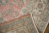 Distressed Sparta carpet corner revealing worn pink and beige pile, original side cord, and fringe.