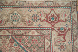 Vintage distressed Persian Tabriz carpet corner with faded Herati patterns in beige, teal, red.
