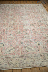Distressed vintage Sparta carpet close-up, showing worn pink, ivory, charcoal floral field.