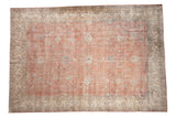 Distressed vintage Sparta carpet with faded blush field, floral palmettes, and light beige border.