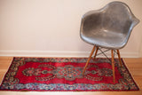 Bold hot pink-red vintage Kerman rug showcasing central blue traditional floral motif.