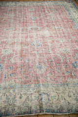 Distressed vintage Sparta carpet showing worn pile, faded red floral patterns.