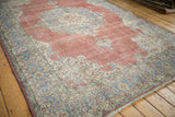 Distressed texture and scrolling ivory and sky blue arabesque border of the vintage Sparta carpet.