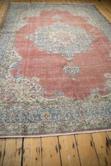 Distressed Turkish Sparta rug corner, dusty burgundy field with ivory and blue scrolling spandrel.