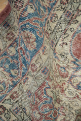Distressed Sparta carpet shows worn pile, revealing blue, red, and beige scrolling motifs.