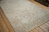 Distressed Tabriz carpet's worn pile, geometric patterns in ivory, beige, and powder blue.