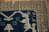 Distressed Oushak rug corner, revealing cobalt blue motifs on a beige field with exposed foundation.