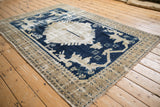 Distressed vintage Oushak rug corner, cobalt blue stylized patterns on worn antique ivory.