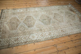 Distressed beige Kurd rug corner, revealing geometric diamond guls and side selvage.