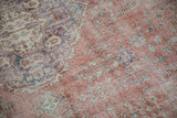 Worn low pile of a vintage Sparta carpet with faded terracotta, violet, and blue floral details.