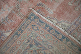 Folded corner of a distressed Sparta carpet showing the machine bound edge, short fringe, and worn hand-knotted pile.