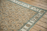 Angled view of a Sparta rug corner showing the abrashed floral border and worn low pile.