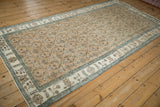 Angled view of a distressed Sparta runner with a sandy field, floral roundels, and pale blue borders.