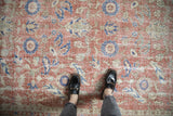 Distressed vintage Sparta rug with faded brick red, blue, and sand floral roundels.